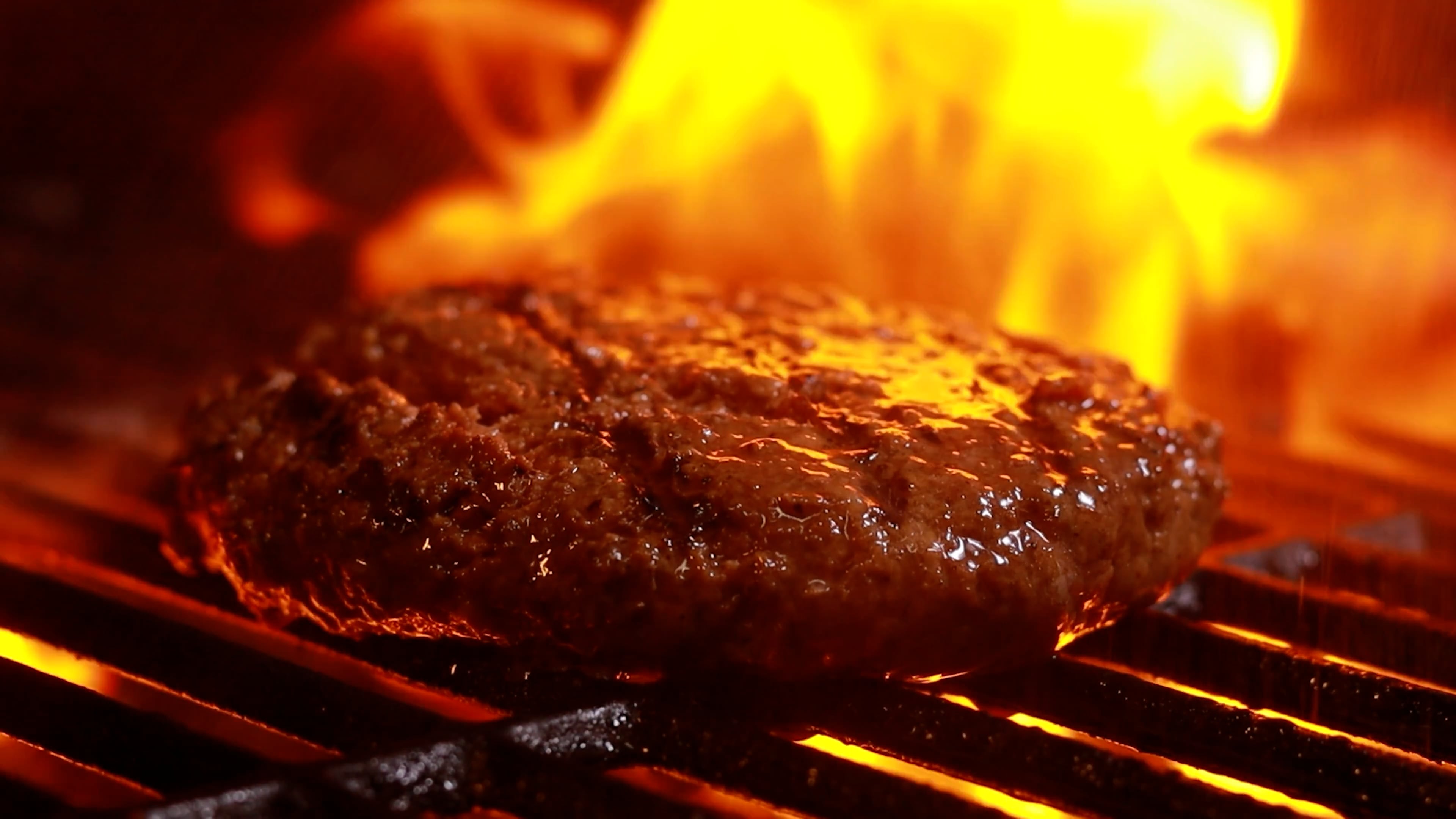 Meat cooking on grill grates over open flames